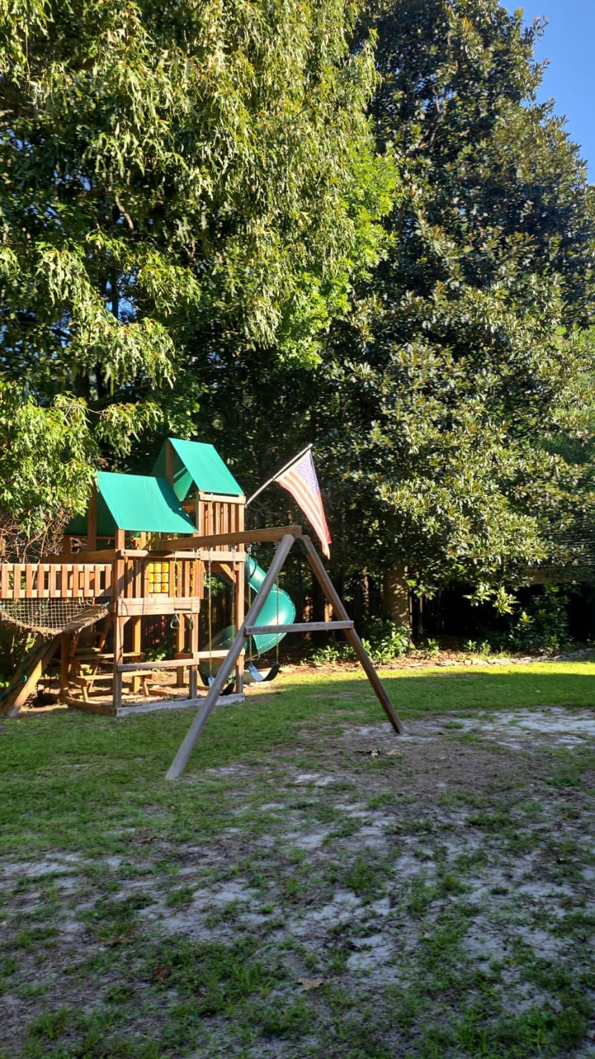 Dense mature tree canopy surrounding a backyard playground in Jacksonville, NC